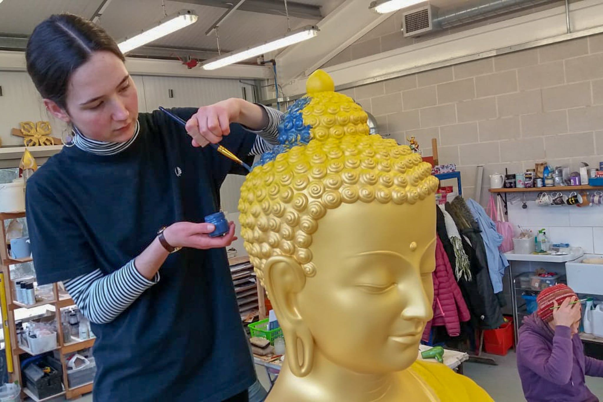 Kunststudio freiwilliger Mitarbeiter arbeitet an Buddha Statue
